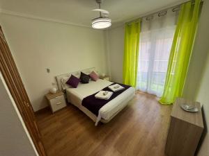 a bedroom with a bed and a window with green curtains at Homely Apartments Mar 3 in Torrevieja +23 photos