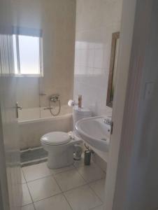 een witte badkamer met een toilet en een wastafel bij On the Beach 20 in Swakopmund