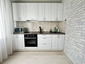 une cuisine avec des placards blancs et un mur en briques dans l'établissement New! 2-комнатная квартира В САМОМ ЦЕНТРЕ ГОРОДА, à Petropavlovsk-Kamtchatski