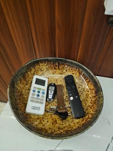 Una bandeja con dos controles remotos y un teléfono celular en Midori by Gatsby Stays, en Ghaziabad
