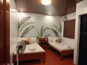 2 Betten in einem Zimmer mit Wandbild in der Unterkunft BALAI MALINAWON - Villa 2 in General Luna