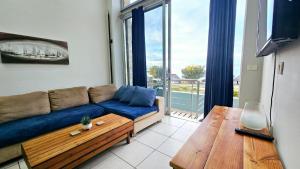 a living room with a blue couch and a wooden table at Nautica 009 Studio Flat in Mossel Bay