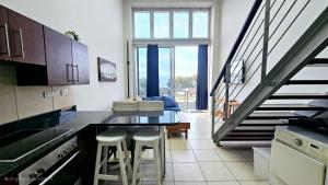 a kitchen with a table and stools and a staircase at Nautica 009 Studio Flat in Mossel Bay +19 photos