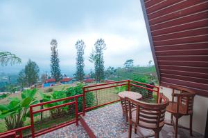a balcony with chairs and a table and a view at Khanzana Cabin and Camp in Kejajar