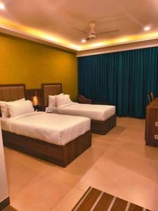 a hotel room with two beds and a television at Parays Fernwoods in Mannārakkāt +4 photos