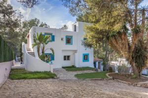 Casa blanca con ventanas azules y árboles en Villa Montecristo, en Montecristo