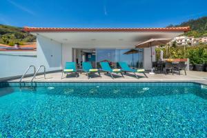 ein Pool mit blauen Stühlen und ein Haus in der Unterkunft OurMadeira - Arco Sun in Arco da Calheta