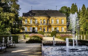 une maison jaune avec une fontaine devant elle dans l'établissement Hotel Kasteel Oost, à Fauquemont
