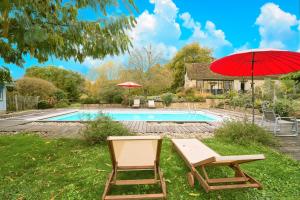 une paire de chaises et un parasol à côté d'une piscine dans l'établissement Loft Ôvebas - Domaine De L 'ô, à Bellacaud