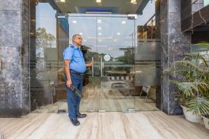 um homem parado em frente a uma janela com um relógio em Hotel Downtown - East of Kailash em Nova Deli