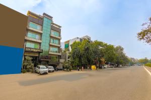 uma rua da cidade com carros estacionados em frente a um edifício em Hotel Downtown - East of Kailash em Nova Deli