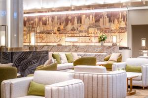 a lobby with white chairs and a wall with a painting at Grande Centre Point Prestige Bangkok in Bangkok