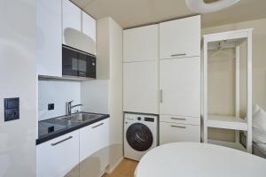 Una cocina blanca con fregadero y lavadora. en Studio 700hm Schruns, en Schruns