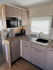 a small kitchen with a sink and a microwave at Caravan by the Sea KW10 in Kinmel Bay +1 photo