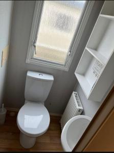 a small bathroom with a toilet and a window at Caravan by the Sea KW10 in Kinmel Bay