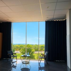 a room with chairs and a table in front of a large window at Ánh Mai Hotel in Bao Loc