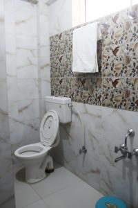 Un baño con un inodoro y una toalla en la pared. en Hotel Samar, en Srinagar