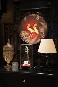 a table with a lamp and a picture of birds at C'Lau Hotel Ninh Binh in Ninh Binh
