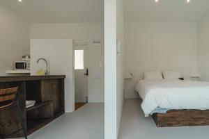 a white bedroom with a bed and a kitchen at Jeju Mureungri The house in Murŭng-ni