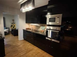 een keuken met zwarte kasten en een magnetron bij Spacious apartment in a quiet area in Narvik