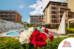 a vase with red and white flowers next to a pool at Apartment Tourist Complex Rose Village in Sunny Beach
