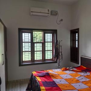 a bedroom with a bed with a colorful quilt on it at Sithara in Kannur