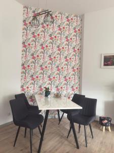 een eettafel met 2 stoelen en behang bij Kamienica Apartament Iława PIERWSZE PIĘTRO in Iława