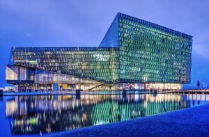 a large glass building with its reflection in the water at Candlewood Suites Reykjavik by IHG in Reykjavík
