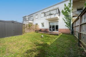 einen Hof vor einem weißen Gebäude in der Unterkunft Chez Adrien au Haillan Appt rez de chaussée jardin in Le Haillan