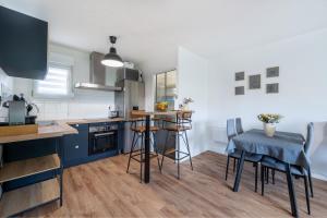 eine Küche mit blauen Schränken sowie einem Tisch und Stühlen in der Unterkunft Chez Adrien au Haillan Appt rez de chaussée jardin in Le Haillan + 6 Fotos