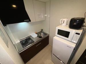 a small kitchen with a microwave and a sink at Guest House Ogusu INN in Fukuoka
