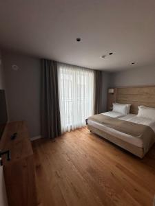 ein Schlafzimmer mit einem großen Bett und einem großen Fenster in der Unterkunft Alpine Eden Hideaway in Râșnov