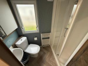 ein kleines Badezimmer mit Toilette und Dusche in der Unterkunft Oscars Inn, West Sands, Seal Bay Resort in Selsey