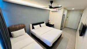 a bedroom with two beds and a ceiling fan at Aman Inn Hotel in Melaka