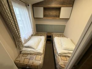 zwei Betten in einem kleinen Zimmer mit Fenster in der Unterkunft Oscars Inn, West Sands, Seal Bay Resort in Selsey