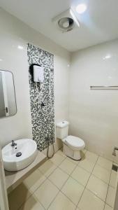 a white bathroom with a toilet and a sink at Aman Inn Hotel in Melaka +22 photos