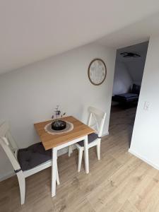 a dining room table with two chairs and a clock on the wall at RheinSchatz Apartments 3 in Oberwesel