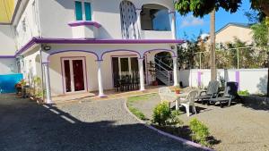 ein rosa und weißes Haus mit einem Tisch und Stühlen in der Unterkunft Bella Melody's Paradise in Flic-en-Flac