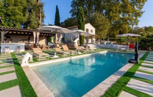 ein Pool mit Stühlen und Sonnenschirmen in einem Hof in der Unterkunft Bastide Blanche in Les Arcs sur Argens