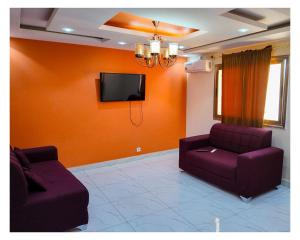 a living room with two purple couches and a flat screen tv at Hôtel Ami Bamba in Mbour