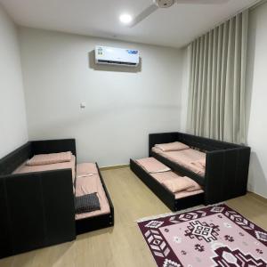 a room with two beds and a tv on the wall at Alhana Oasis in Badīyah
