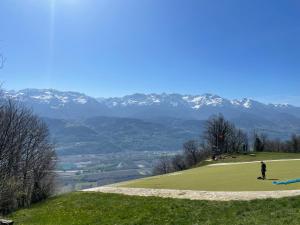 a person standing on a golf course with mountains in the background at Auberge des Skieurs in La Bresse