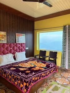 a bedroom with a large bed and two chairs at Danda Nagraja Homestay in Byānsghāt