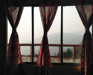 a window with a view of a mountain at Brookland Stays in Pedong +7 photos