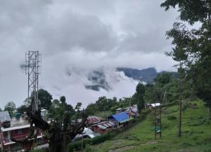 a small village on a hill with clouds in the sky at Brookland Stays in Pedong