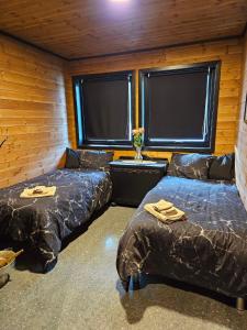 SørelvmoにあるArctic Sealodge Malangen cabin 4 Sæterberganのベッド2台、テーブル、窓2つが備わる客室です。 +30枚の写真