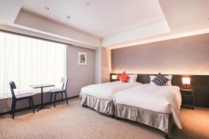 a hotel room with two beds and a desk at KABIN Kyoto in Kyoto