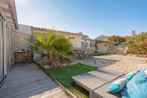 a backyard with a wooden deck and a palm tree at Villa L’hirondelle in La Michelière