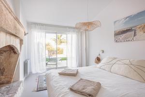 a white bedroom with a bed and a large window at Villa L’hirondelle in La Michelière