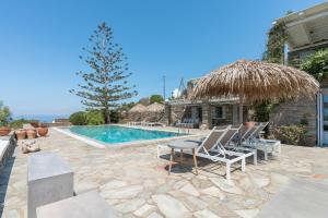 a villa with a swimming pool with chairs and a straw umbrella at Villa Néréides in Koundouros